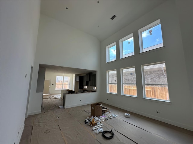 unfurnished living room with baseboards and a towering ceiling