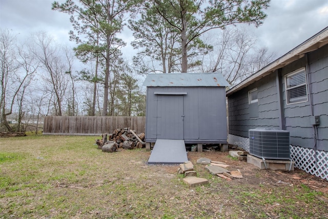 view of yard with an outbuilding, central AC unit, a storage unit, and fence