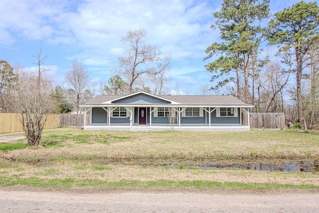 view of front of property with a porch, a front yard, and fence