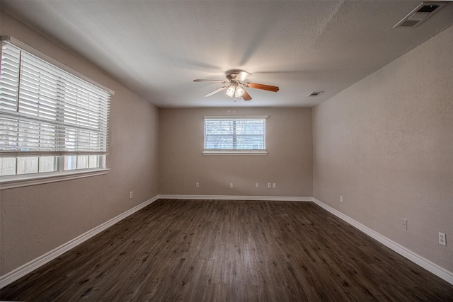 spare room with visible vents, baseboards, a ceiling fan, and dark wood-style flooring