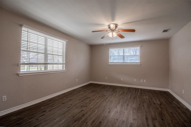 spare room with visible vents, dark wood-style floors, baseboards, and ceiling fan