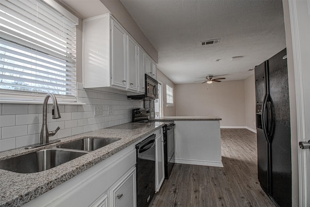 kitchen with visible vents, black appliances, a sink, dark wood finished floors, and white cabinets