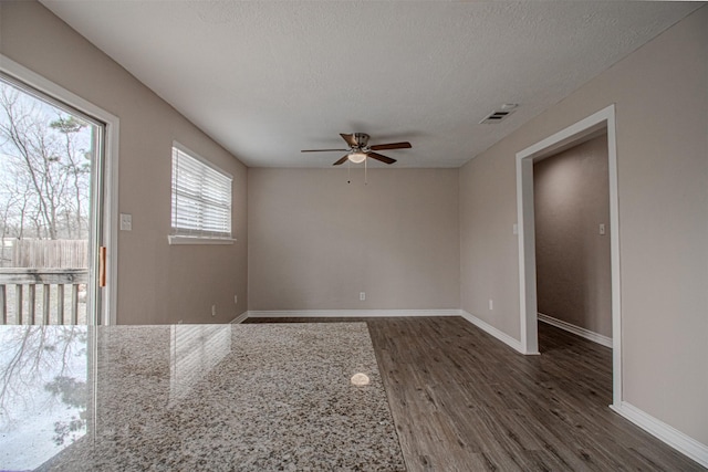 unfurnished room featuring visible vents, ceiling fan, baseboards, wood finished floors, and a textured ceiling