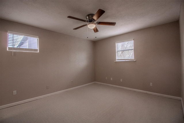 carpeted empty room with a textured ceiling, baseboards, and a ceiling fan