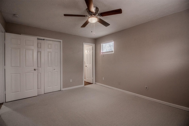 unfurnished bedroom with baseboards, carpet floors, ceiling fan, a closet, and a textured ceiling