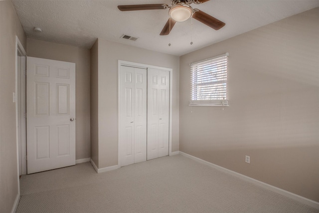 unfurnished bedroom with visible vents, baseboards, a closet, a textured ceiling, and light colored carpet