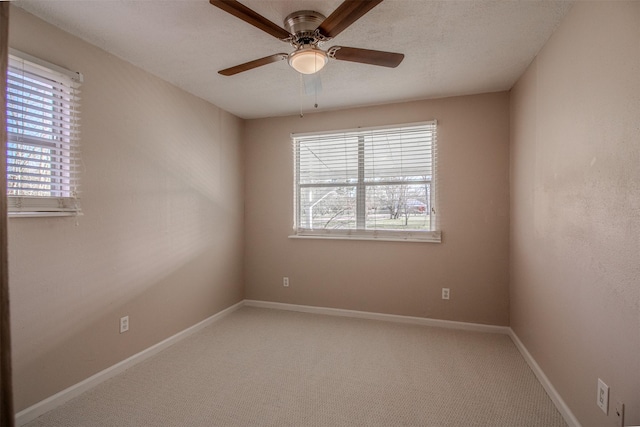 unfurnished room featuring plenty of natural light, light colored carpet, baseboards, and ceiling fan