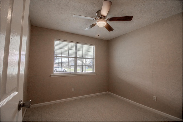 carpeted spare room with ceiling fan, baseboards, and a textured ceiling