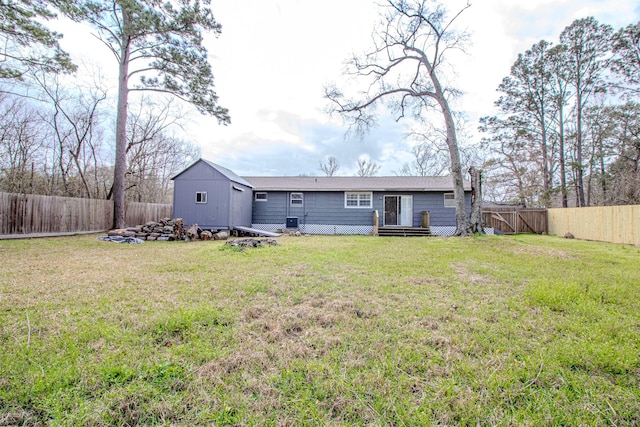 rear view of property featuring a lawn, a fenced backyard, a storage shed, and an outdoor structure