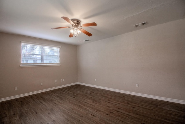 spare room featuring a ceiling fan, dark wood-style floors, visible vents, and baseboards