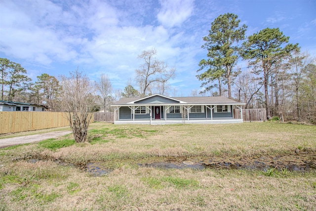 view of front of home with a porch, fence, and a front lawn