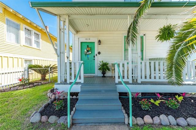 doorway to property featuring covered porch and fence