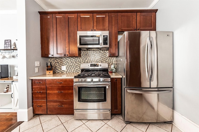 kitchen featuring backsplash, crown molding, baseboards, light tile patterned floors, and stainless steel appliances