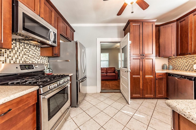 kitchen featuring crown molding, ceiling fan, light tile patterned floors, decorative backsplash, and appliances with stainless steel finishes