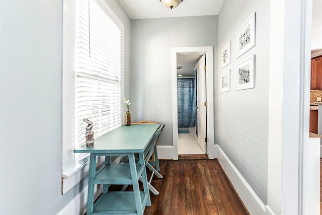 corridor with dark wood-type flooring and baseboards