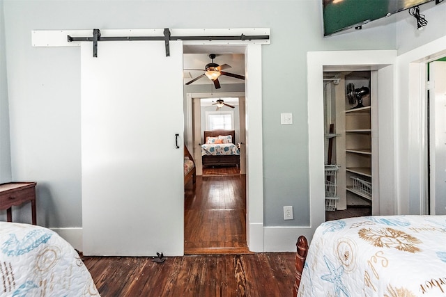 bedroom featuring baseboards, a barn door, and wood finished floors