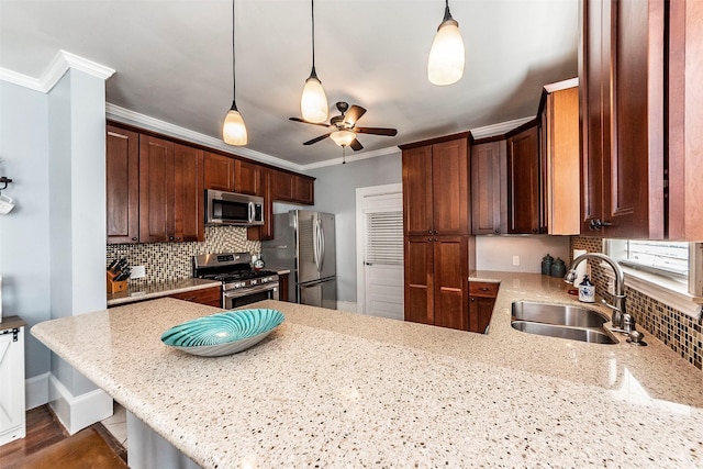 kitchen featuring crown molding, ceiling fan, a peninsula, stainless steel appliances, and a sink