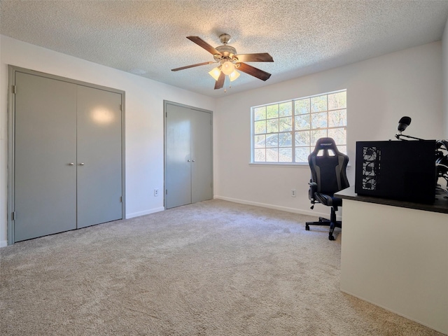 carpeted office featuring baseboards, a textured ceiling, and a ceiling fan