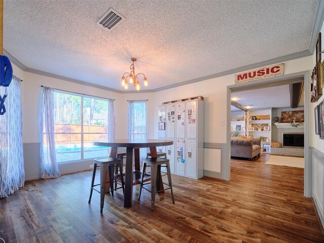 dining area featuring visible vents, dark wood finished floors, a textured ceiling, crown molding, and a notable chandelier