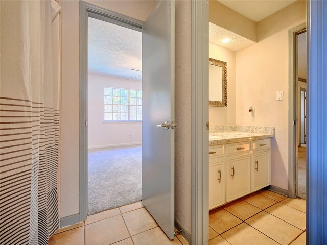 bathroom with tile patterned flooring, vanity, baseboards, and a textured ceiling