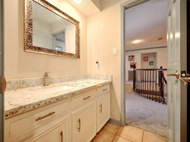 bathroom with tile patterned floors, visible vents, a textured ceiling, and vanity