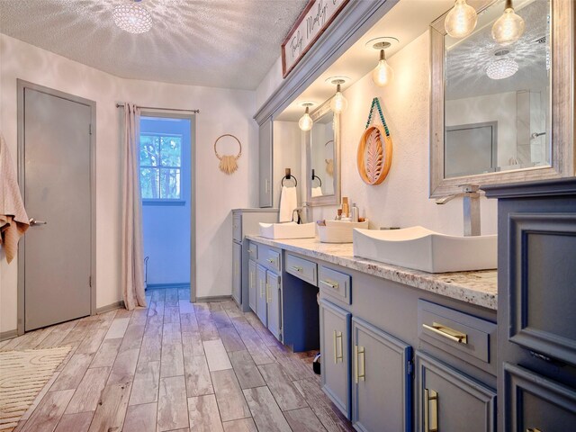 bathroom featuring wood finish floors, baseboards, a textured ceiling, and vanity