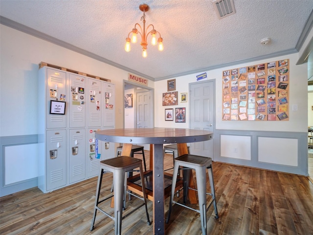 dining area with an inviting chandelier, wood finished floors, visible vents, and a textured ceiling