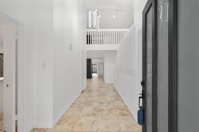 corridor with baseboards and a towering ceiling