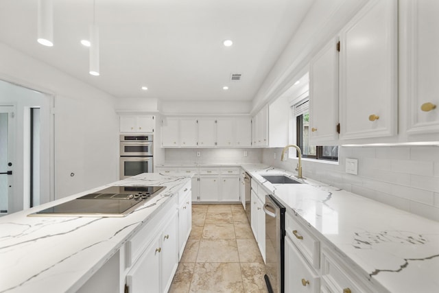 kitchen featuring backsplash, light stone countertops, appliances with stainless steel finishes, white cabinets, and a sink