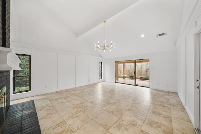 empty room featuring visible vents, a fireplace, an inviting chandelier, a decorative wall, and high vaulted ceiling