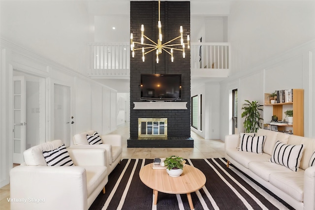 living area with tile patterned flooring, a notable chandelier, a fireplace, and a high ceiling