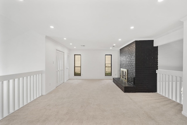 unfurnished living room featuring recessed lighting, carpet floors, a brick fireplace, and crown molding