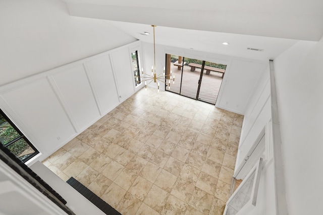 empty room with recessed lighting, visible vents, lofted ceiling, and a decorative wall