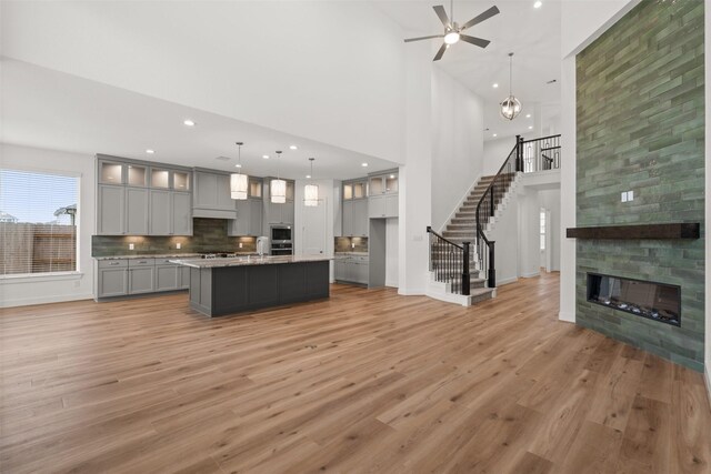 16174 Rustling Woods Rd, Conroe, TX 77302 - kitchen with gray cabinetry, a high ceiling, light wood finished floors, ceiling fan, and glass insert cabinets