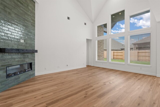 16174 Rustling Woods Rd, Conroe, TX 77302 - unfurnished living room with light wood-style floors, a fireplace, baseboards, and high vaulted ceiling