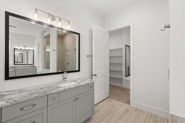 16174 Rustling Woods Rd, Conroe, TX 77302 - bathroom with wood finished floors, vanity, and tiled shower