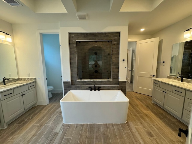 16174 Rustling Woods Rd, Conroe, TX 77302 - full bathroom with wood finished floors, a stall shower, a soaking tub, two vanities, and recessed lighting