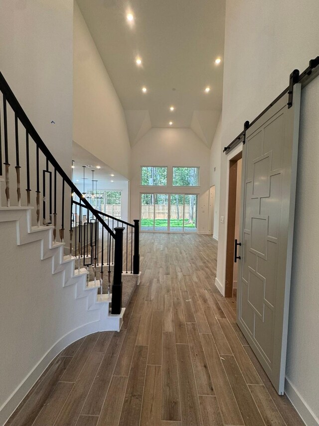 16174 Rustling Woods Rd, Conroe, TX 77302 - staircase featuring a barn door, wood finished floors, recessed lighting, baseboards, and high vaulted ceiling