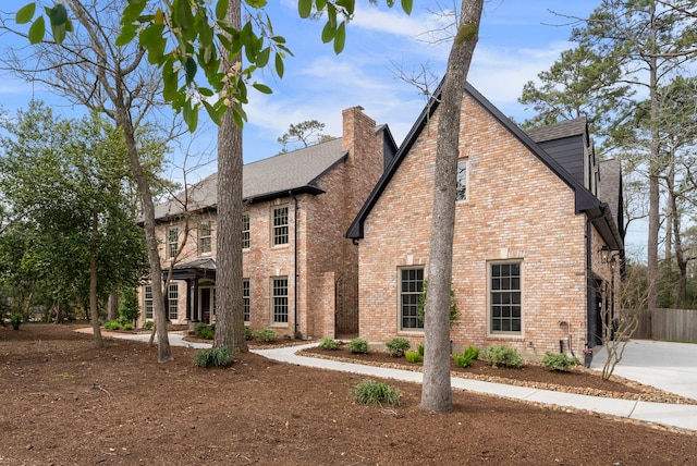 exterior space with fence, brick siding, roof with shingles, and a chimney