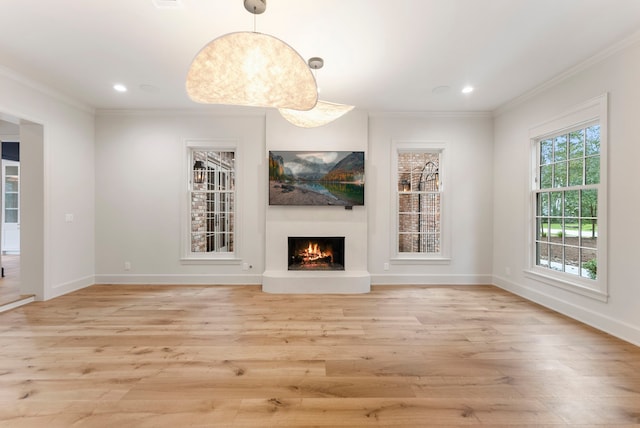 unfurnished living room with light wood finished floors, recessed lighting, a lit fireplace, and ornamental molding