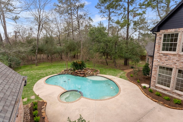 view of swimming pool featuring a lawn and a pool with connected hot tub