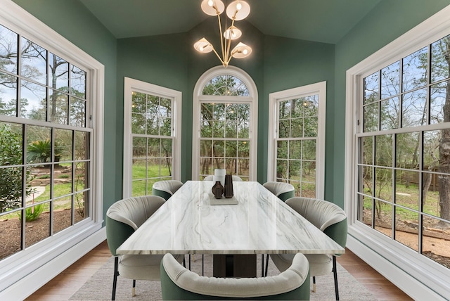 sunroom / solarium featuring an inviting chandelier, a healthy amount of sunlight, and lofted ceiling