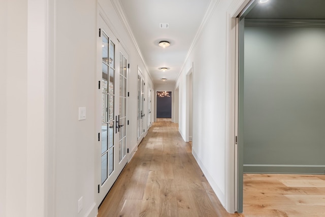 hallway with baseboards, ornamental molding, and light wood finished floors