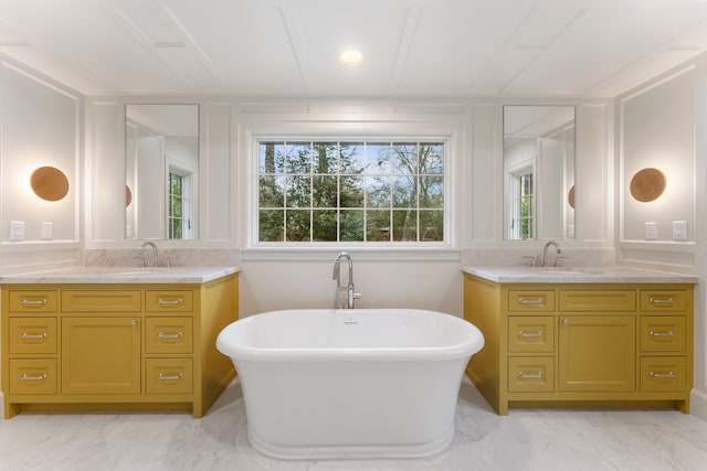 bathroom with a freestanding tub, marble finish floor, and a sink