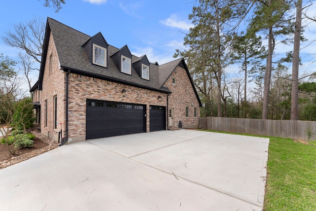 view of side of home featuring brick siding, driveway, and fence