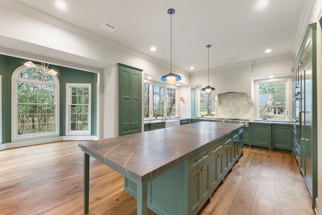 kitchen featuring visible vents, premium range hood, green cabinetry, dark countertops, and light wood-type flooring