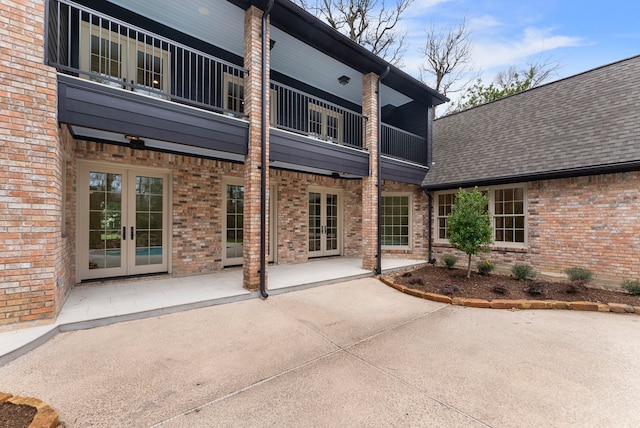 rear view of house featuring brick siding, french doors, a shingled roof, and a patio