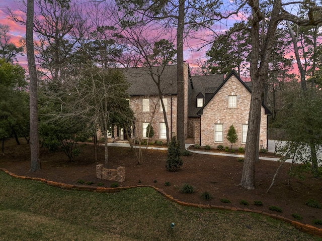 view of front of house featuring stone siding and roof with shingles