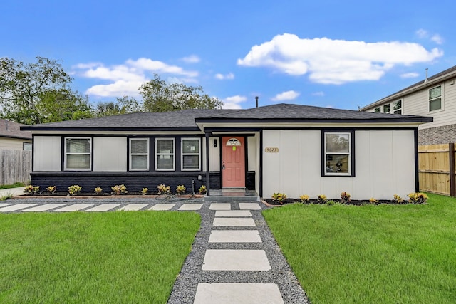 view of front facade with board and batten siding, a front yard, and fence