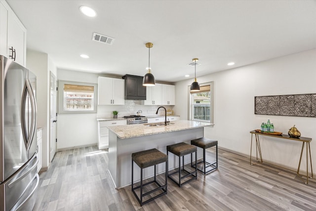 kitchen featuring visible vents, light wood-style flooring, a sink, appliances with stainless steel finishes, and backsplash